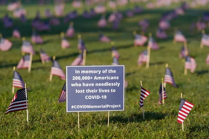 Activists from the COVID Memorial Project mark the deaths of 200,000 lives lost in the U.S. to COVID-19 after placing thousands of small American flags places on the grounds of the National Mall in Washington.
